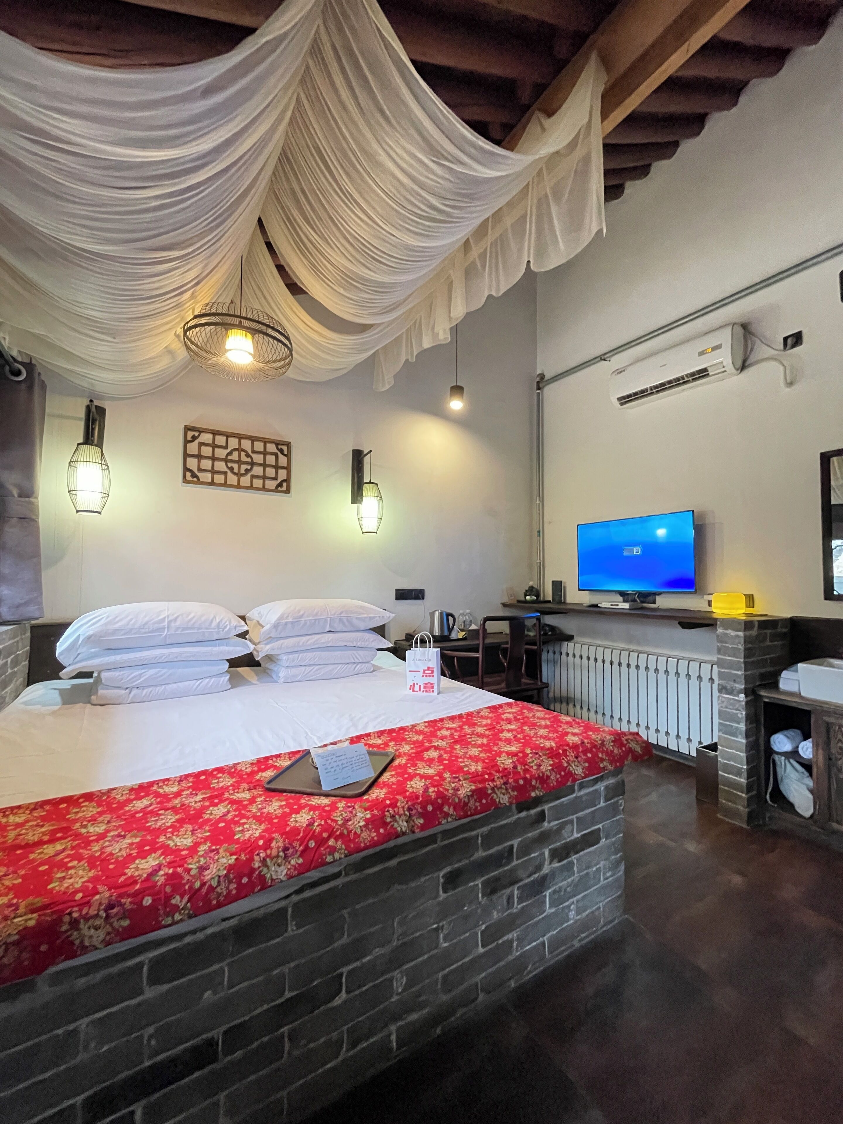 A hotel room with a bed, a desk, a television, and an air conditioning unit.