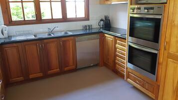 Una cocina con armarios de madera, lavavajillas, cafetera y dos hornos.