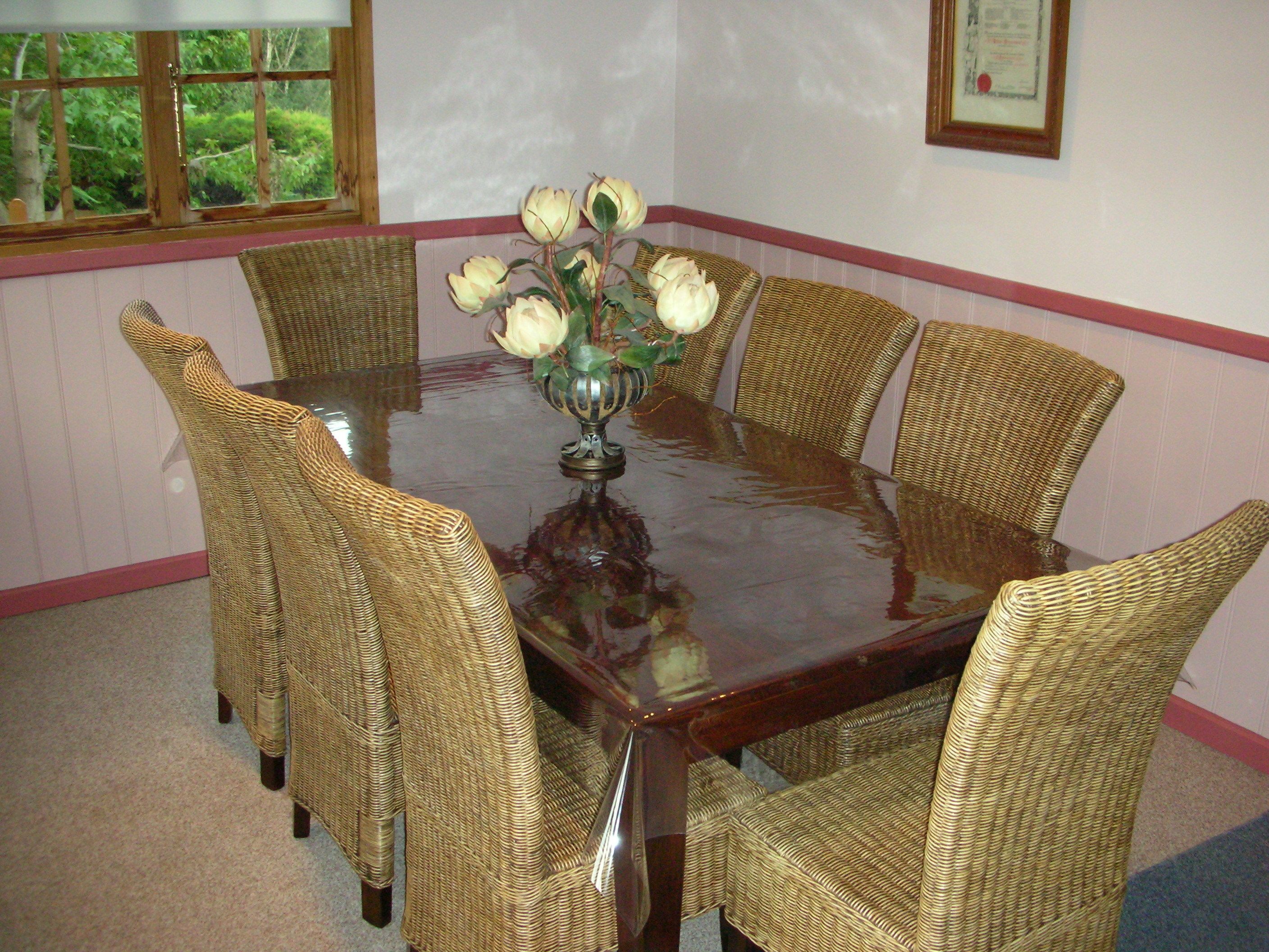 Une table à manger entourée de chaises en osier, avec un vase de fleurs placé au centre.