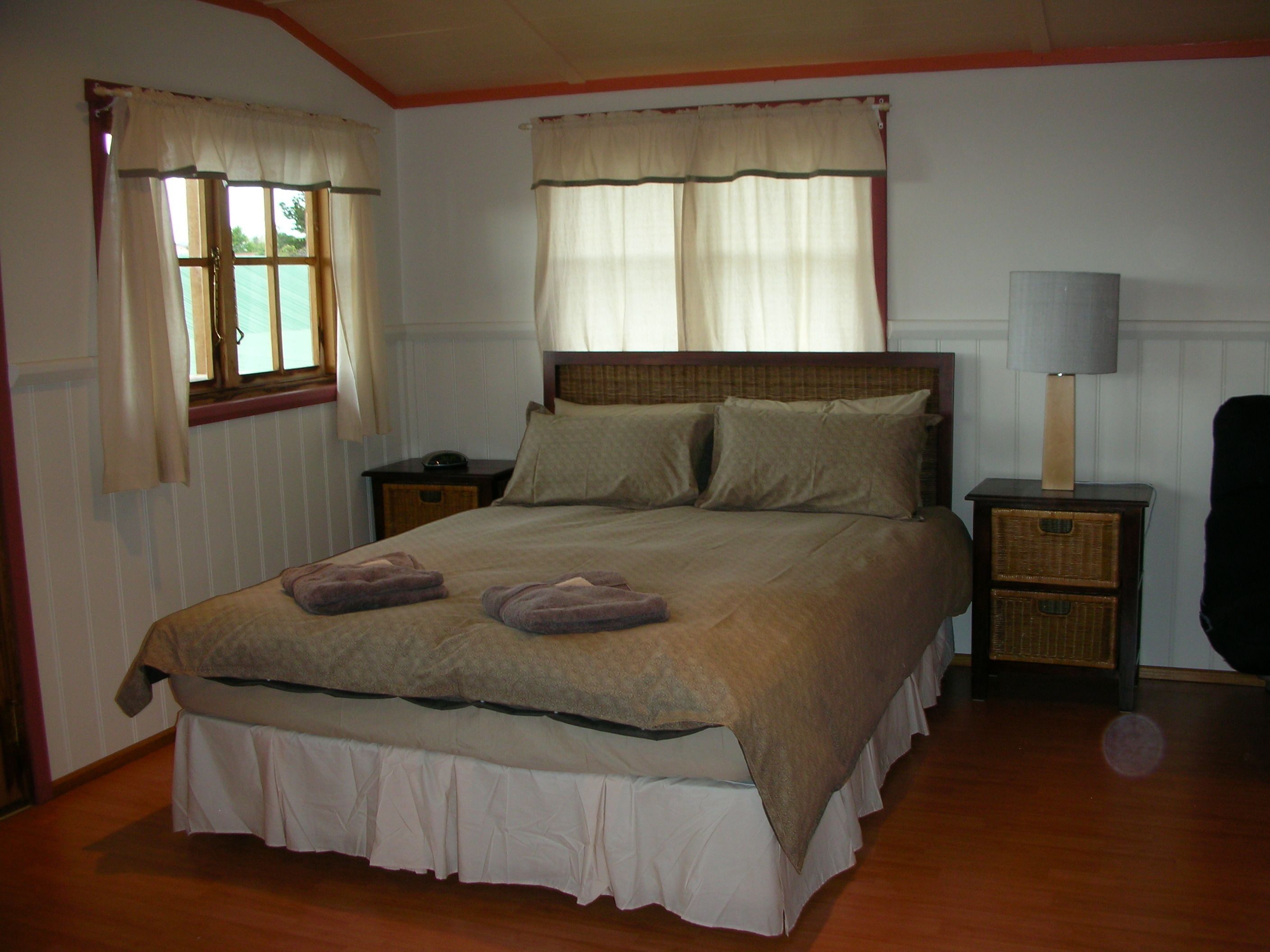 A bedroom with a bed, two bedside tables, a lamp, and curtains.