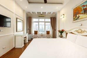 Ein Hotelzimmer mit einem großen Bett, einem Schreibtisch mit Stuhl, einem Fernseher und einem Bild an der Wand.