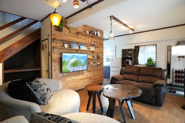 Ein modernes Wohnzimmer mit einer Wand aus Holzpaneelen, einem Flachbildfernseher, einem braunen Ledersofa und einem kleinen runden Tisch.