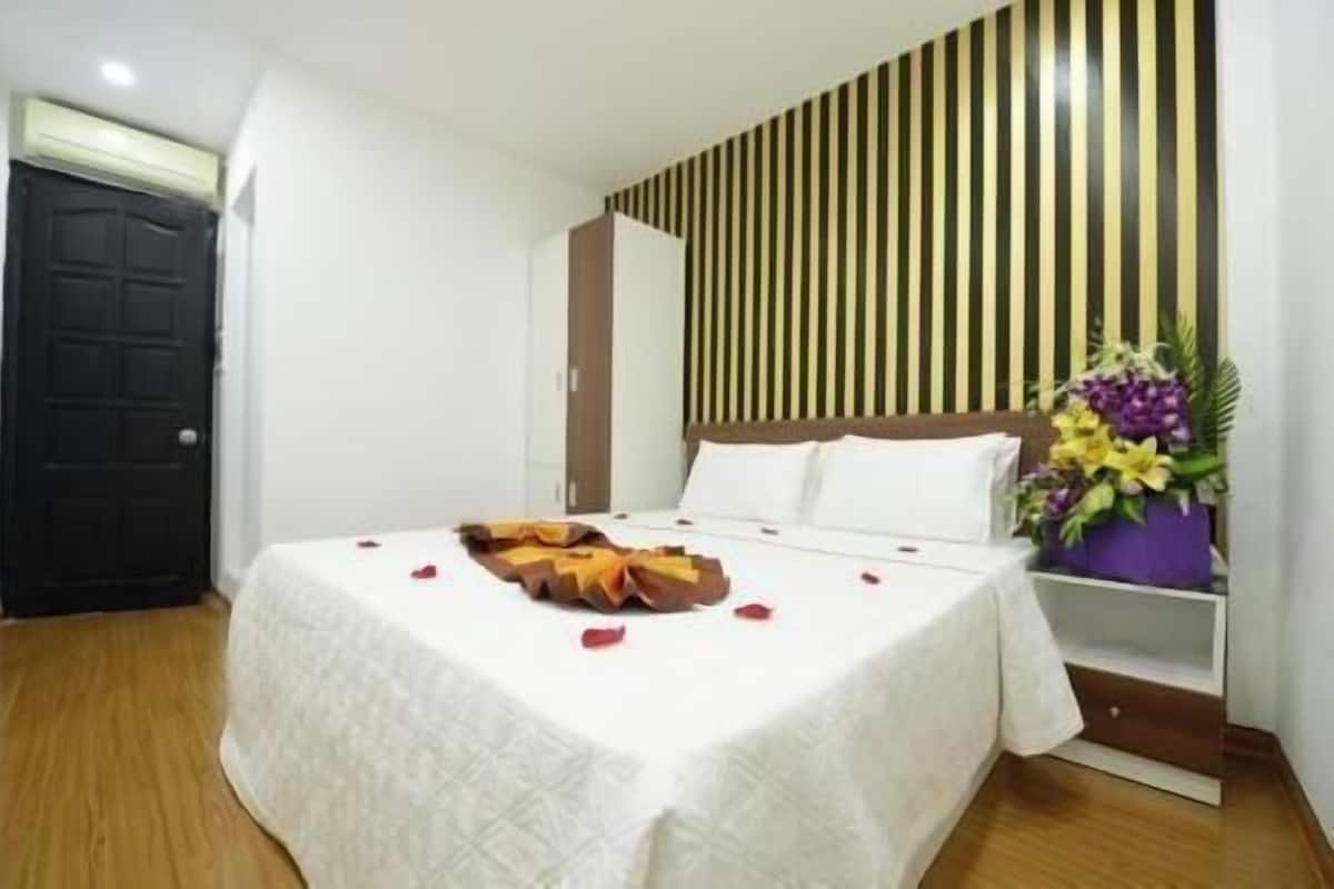 Ein Hotelzimmer mit Bett, einer Holzhakenschrankwand, einer Tür und einer Blumenkomposition.