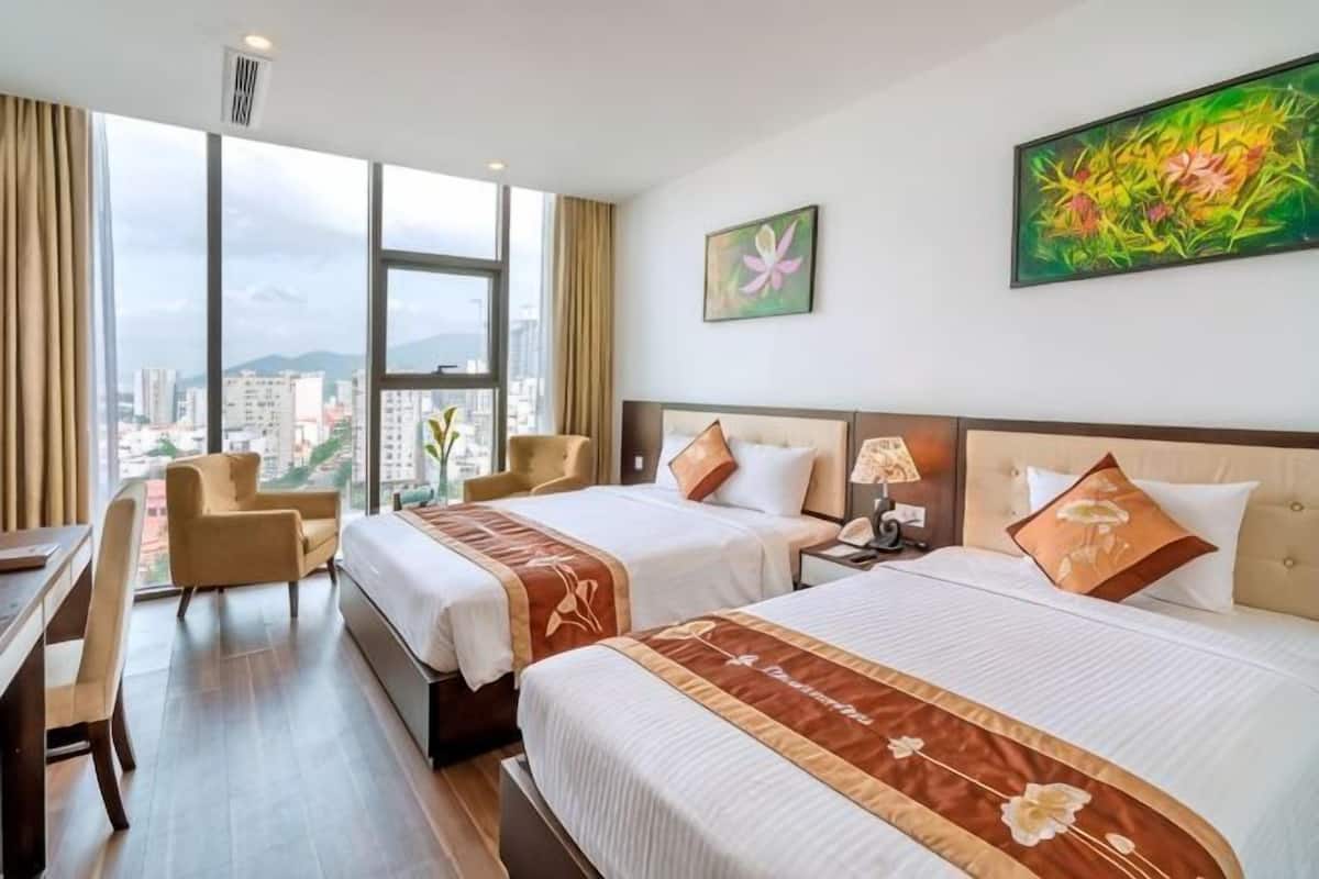 Habitación de hotel con dos camas, un escritorio y una silla.
