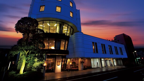 Un hotel moderno con fachada curva, ventanas amplias y una entrada bien iluminada.