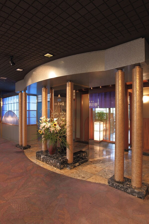 A lobby with a curved ceiling, large windows, and a central floral arrangement. - Hotel Kinsuien (Saiki)