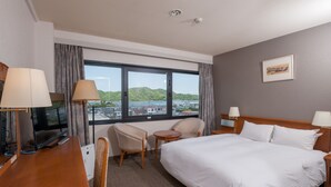 Habitación de hotel con una cama grande, dos sillas, un escritorio con computadora y televisión.