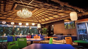 A restaurant with a thatched roof, colorful chairs, and a chandelier. - Hotel K6 Osaka Namba  (Osaka)