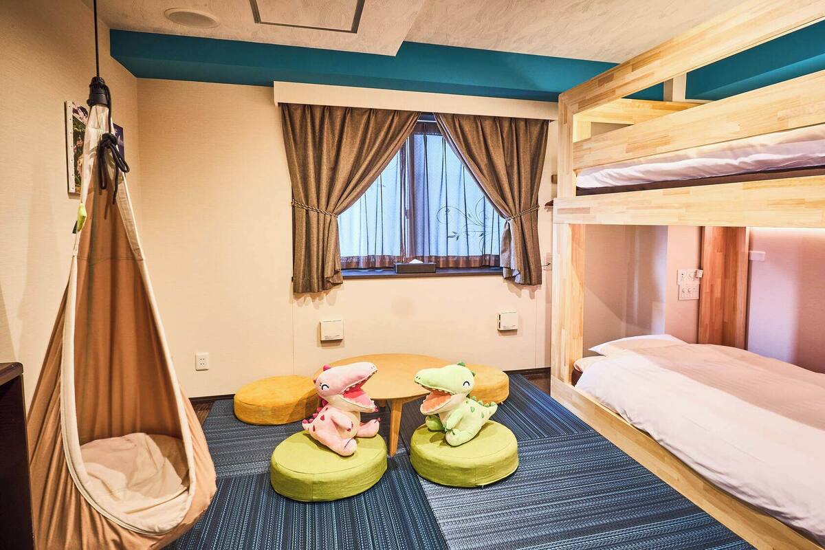 A bunk bed room with a window, a hanging light, and two bean bags with stuffed animals.