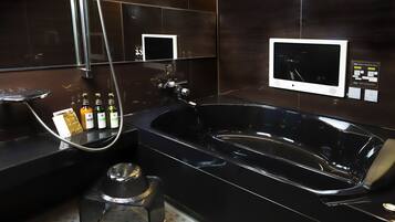 A modern bathroom with a large black bathtub, a handheld showerhead, and two wall-mounted televisions.