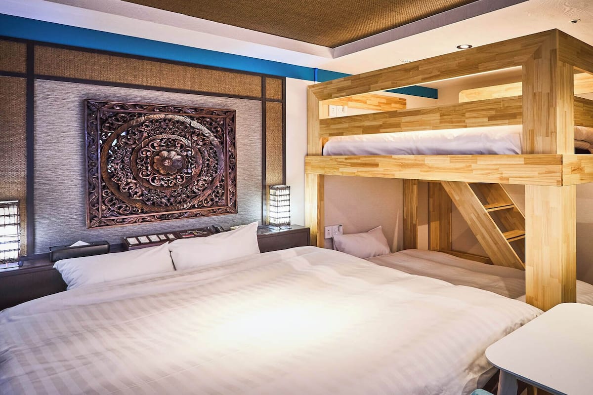 A modern bedroom with a large bed, a wooden bunk bed, and a decorative wall panel.
