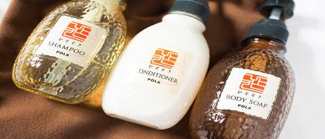 Tres botellas de productos de cuidado corporal sobre una superficie de tela marrón.