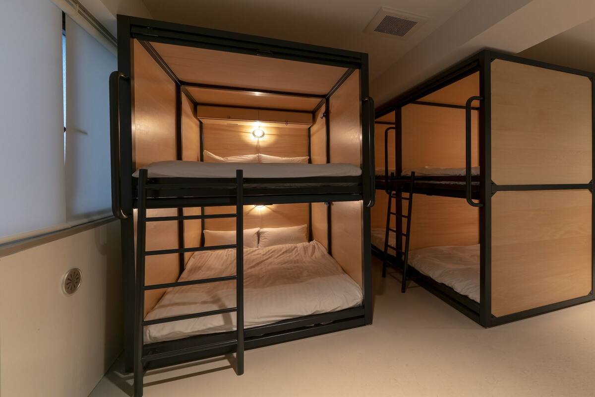 A bunk bed room with a ladder, a light fixture, and a door.