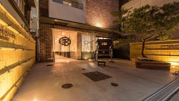 A hotel entrance with a brick facade, a traditional Japanese torii gate, and a covered outdoor seating area.