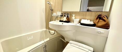 A compact bathroom with a white sink, a toilet, and a shower.