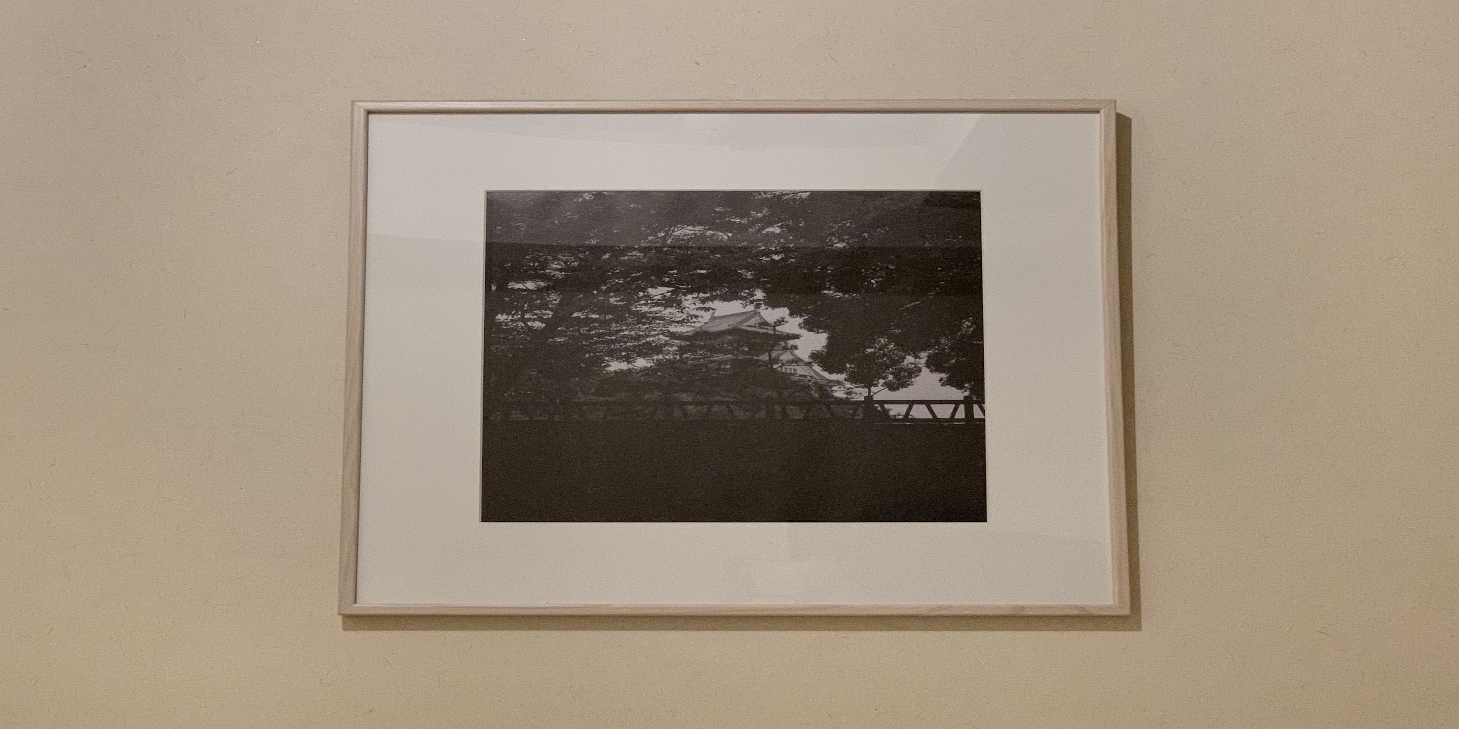 A framed black and white photograph of a coastal scene with a wooden pier and a boat.