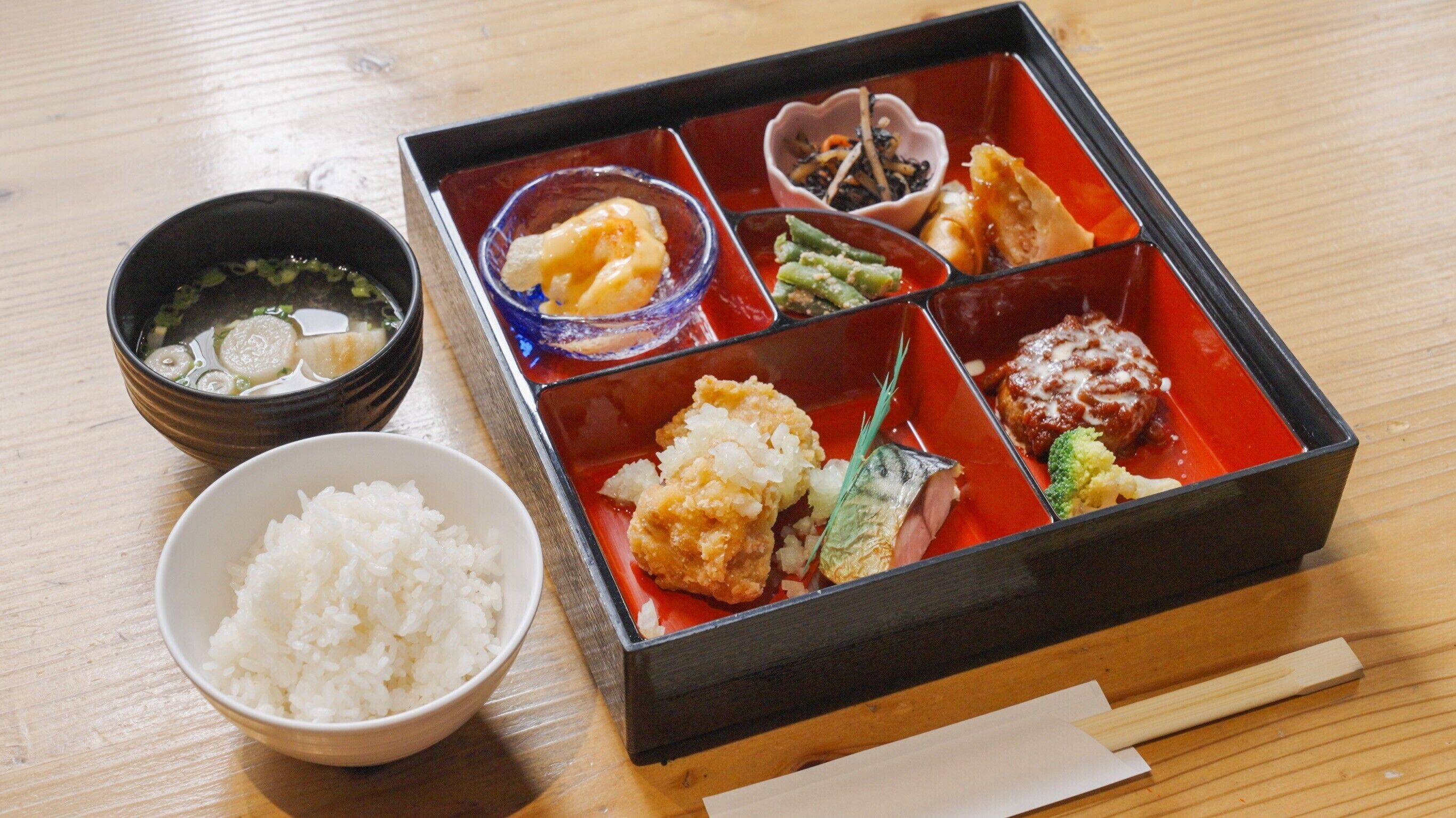 Una comida tradicional japonesa con arroz, sopa y varios platos sobre una mesa de madera.