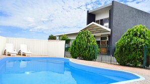 A modern house with a swimming pool, two lounge chairs, and a well-maintained garden. - Tamworth City Motel (South Tamworth)