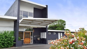 A modern two-story house with a covered patio, a wooden door, and a small outdoor seating area. - Tamworth City Motel (South Tamworth)