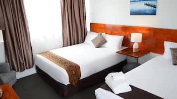 A hotel room with a large bed, a wooden headboard, a nightstand with a lamp, and a painting on the wall.