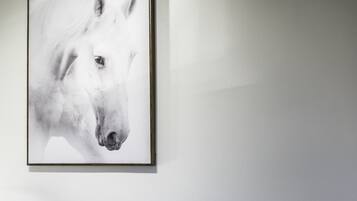 A framed artwork of a horse's head on a plain wall.