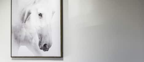A framed artwork of a horse's head on a plain wall.