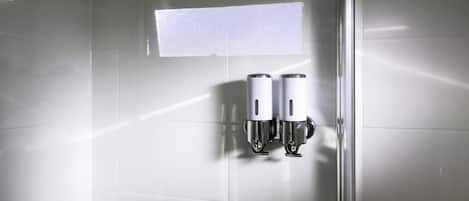 Un baño con dispensador de gel hidroalcohólico fijado a la pared.