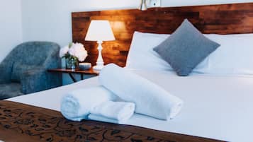Relax in comfort with a neatly made bed, a stylish headboard, and a cozy armchair.