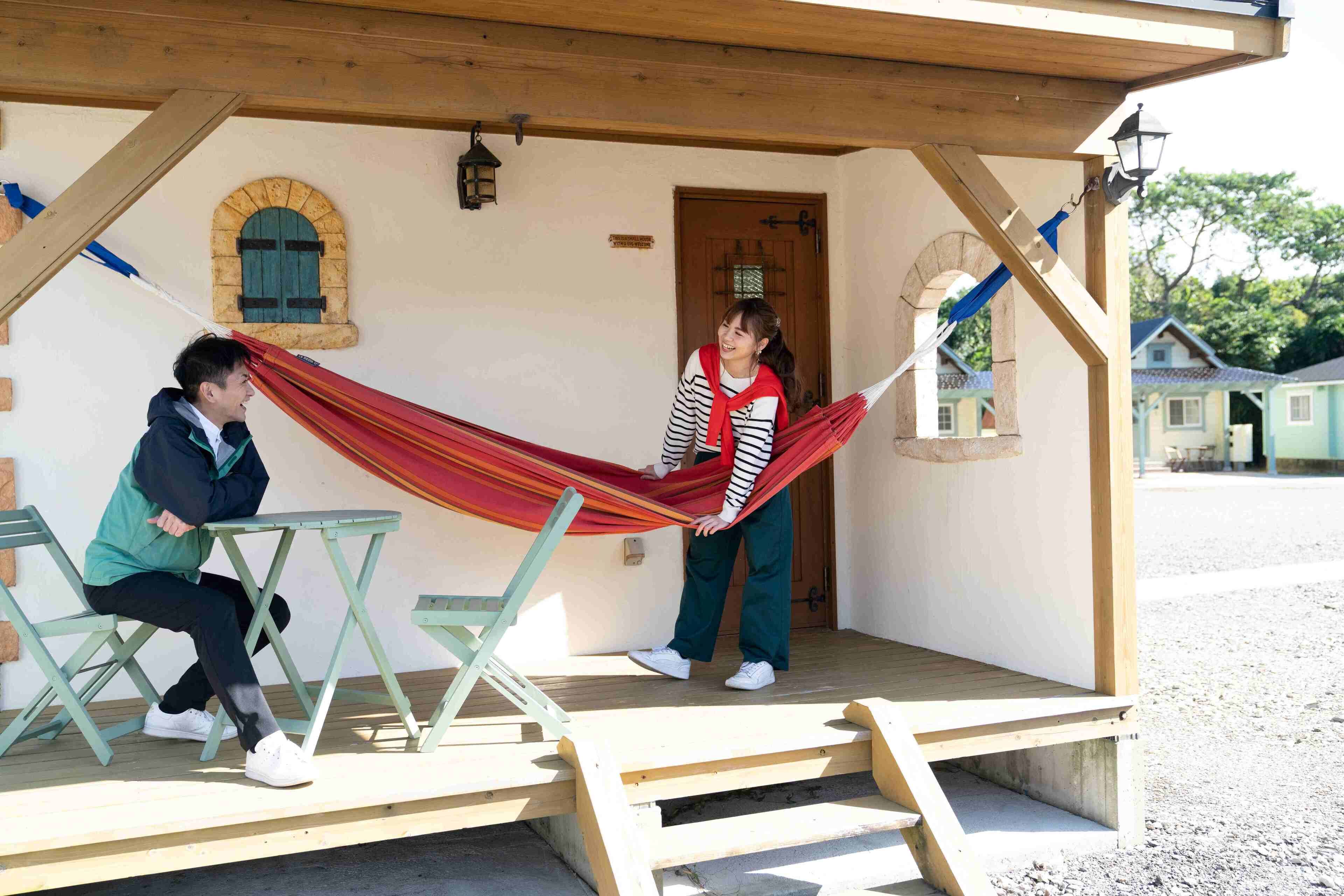 A wooden structure with a hammock, a table, and a bench.