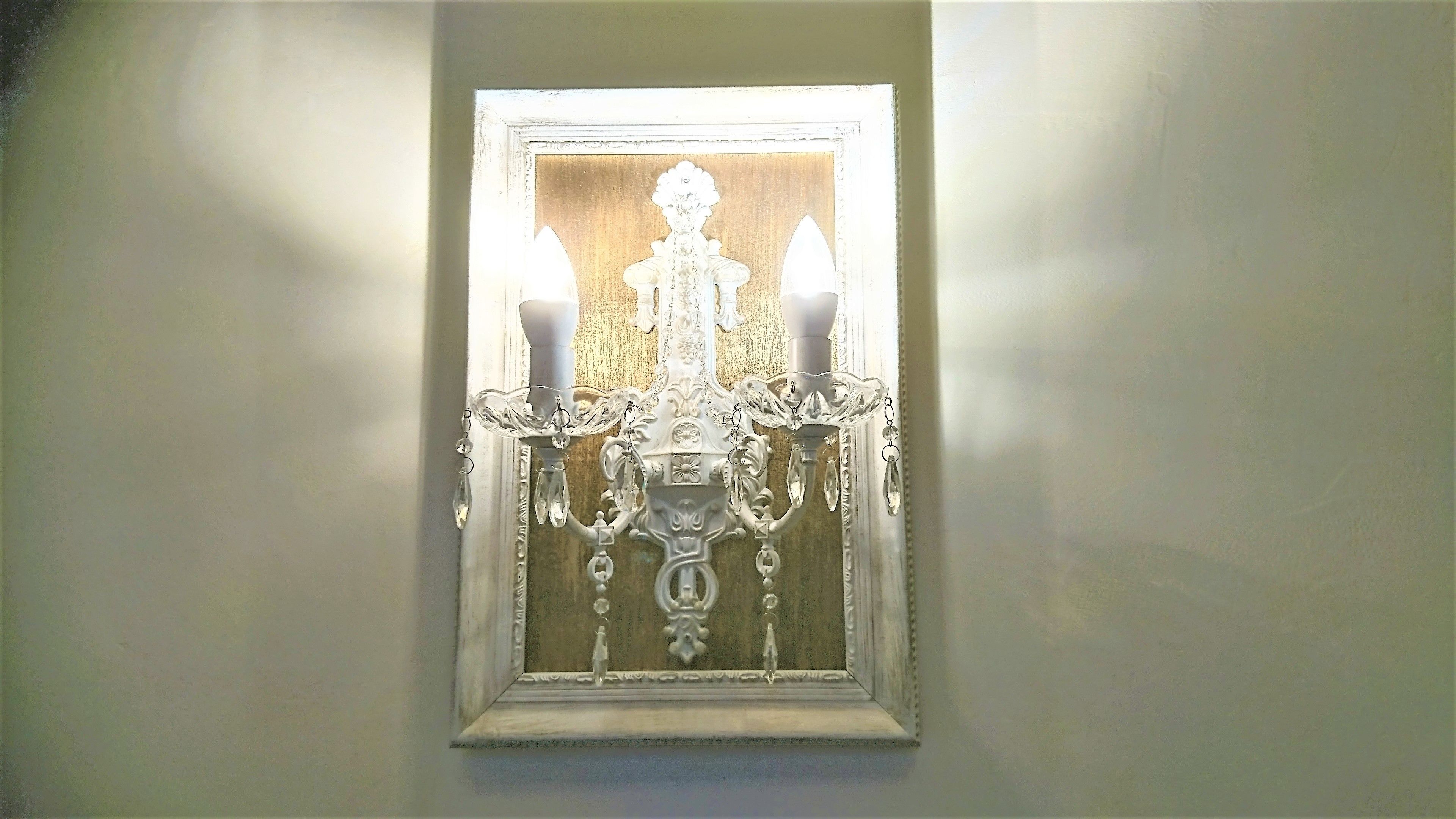A wall-mounted chandelier with multiple arms and crystal decorations.