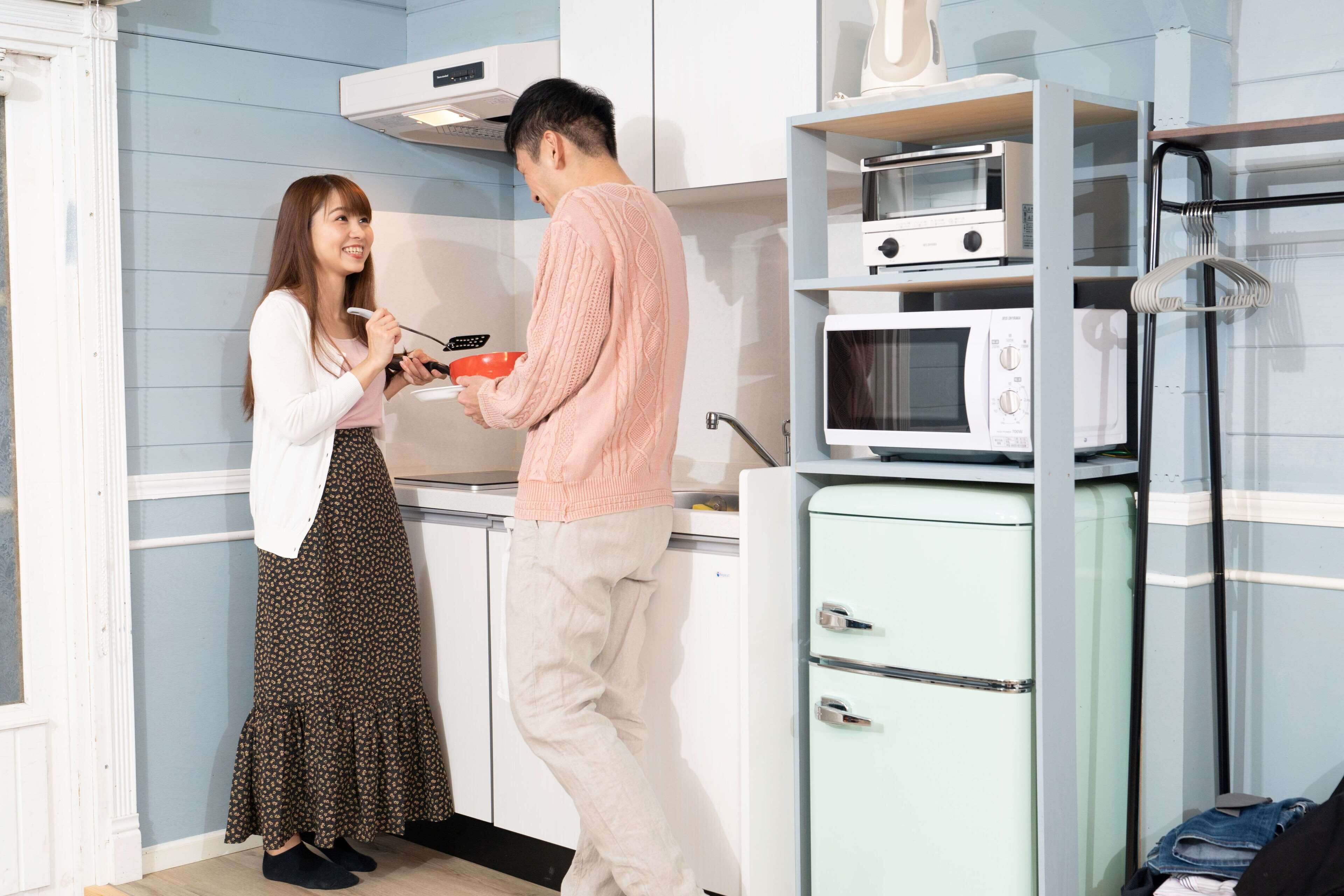 A compact kitchen with white cabinets, a microwave, and a small refrigerator.