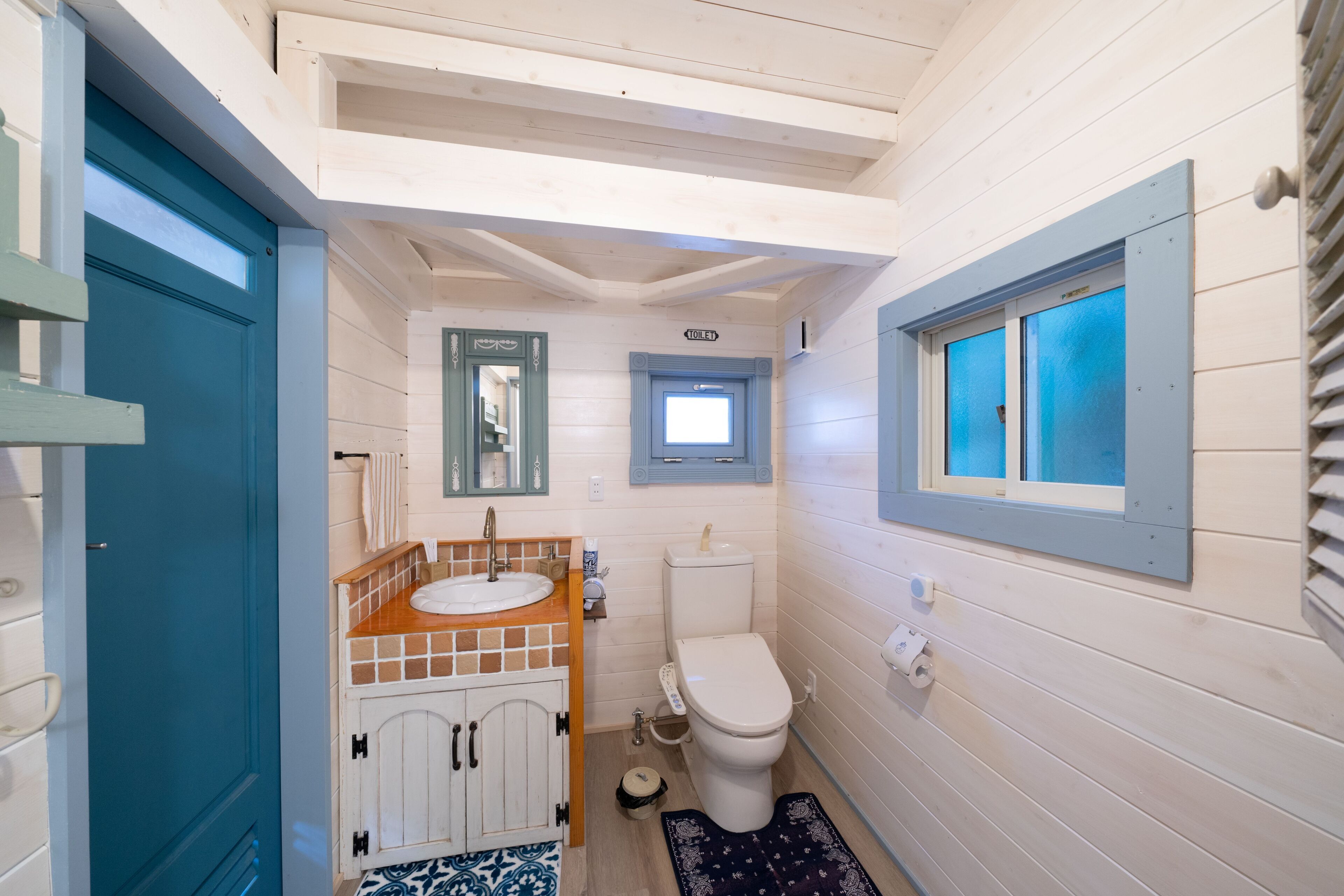 Une petite salle de bain avec un plafond en bois, un lavabo, des toilettes et une petite fenêtre.