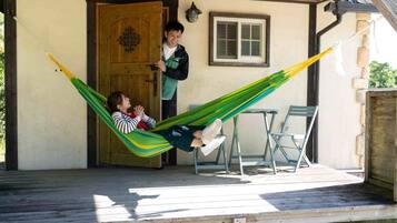 A wooden porch with a hammock, a wooden door, and a window.