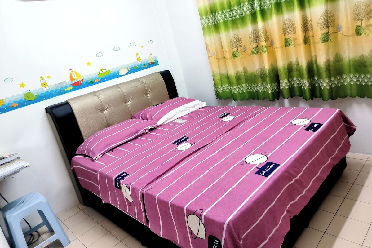 A neatly made bed with striped bedding, a wall-mounted air conditioner, and a decorative wall decal.