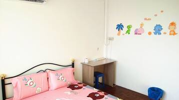A child's bedroom with a bed, pink pillows, a desk, and wall decorations.