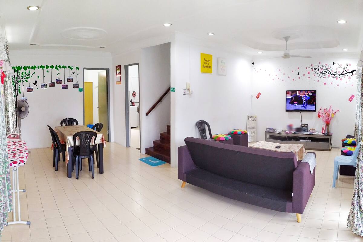 A living room with a sofa, TV, and children's toys. There is a dining area with chairs and a table.