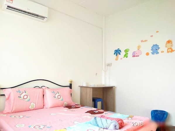 Un dormitorio con cama, almohadas, un escritorio y un adhesivo en la pared.