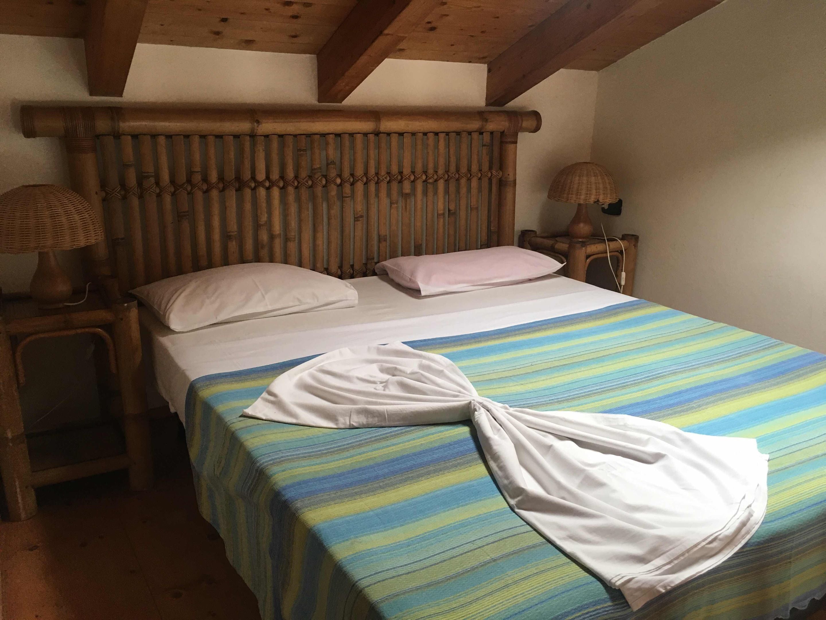 Een bed met een gestreept dekbedovertrek, twee kussens en een witte handdoek erop.
