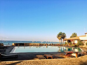A pool area with lounge chairs and a view of the sea. - Porto Antigo (Sal)