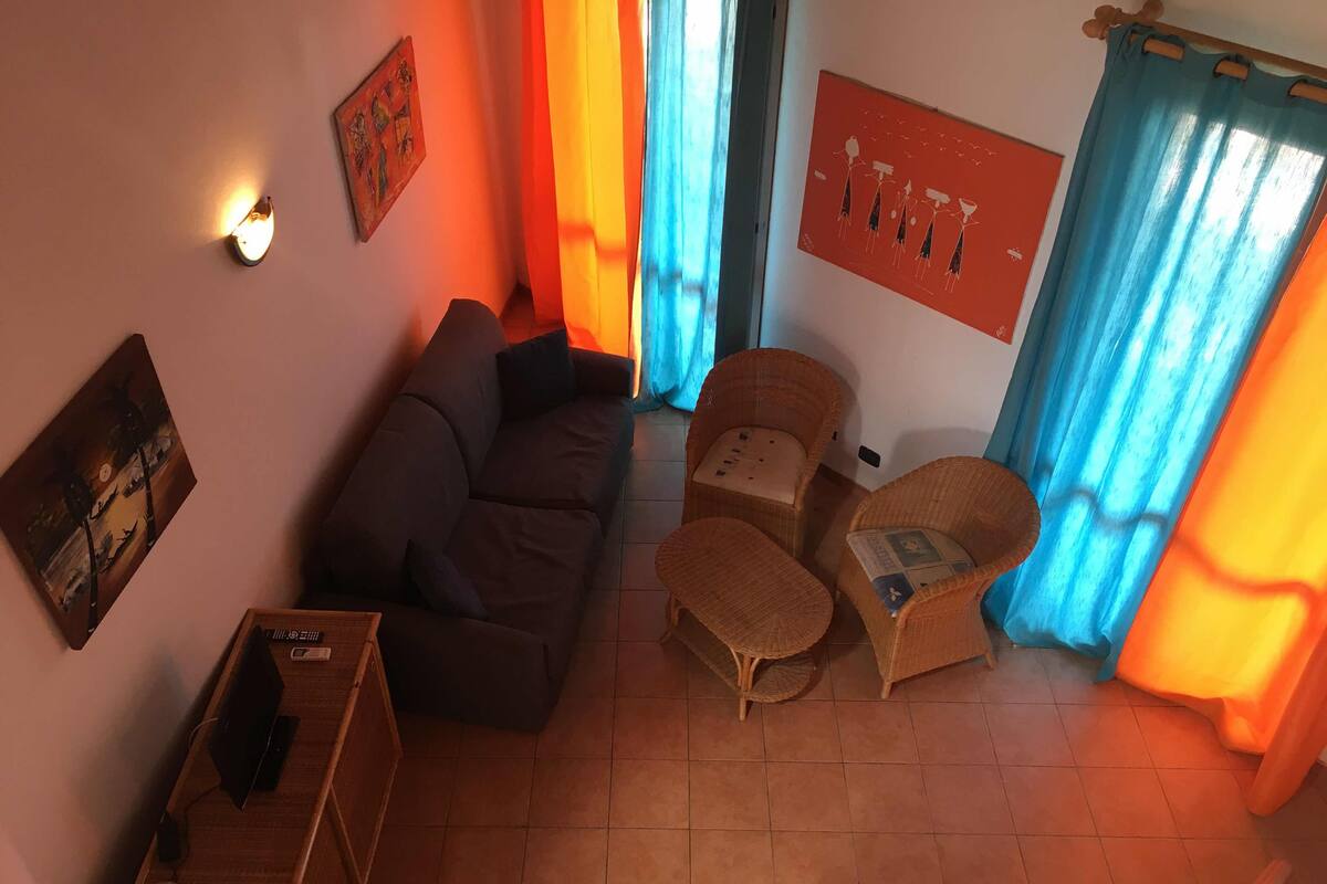A living room with a sofa, two armchairs, a small table, and a television.