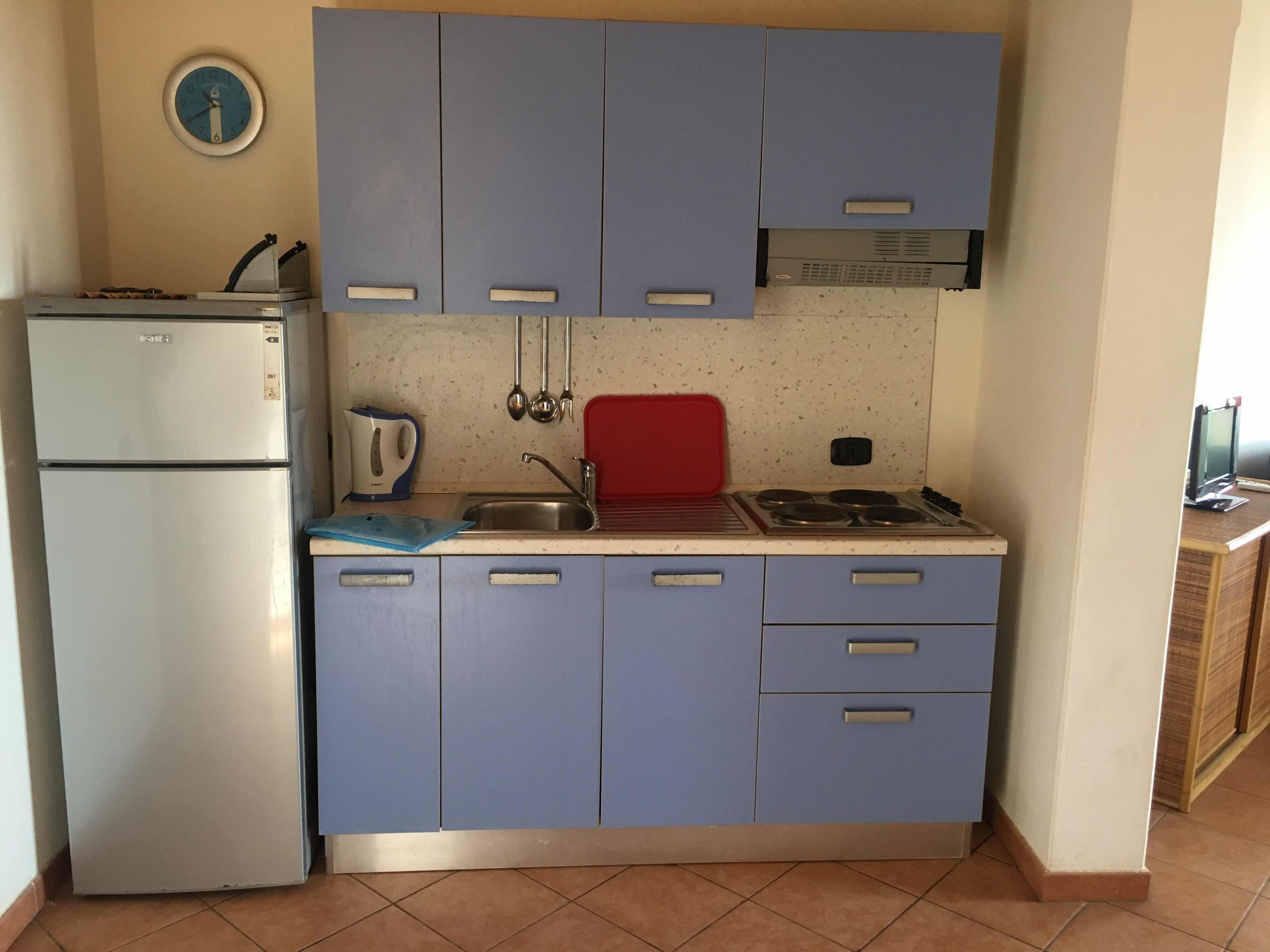 Una cocina compacta con refrigerador, estufa, lavaplatos y gabinetes azules.