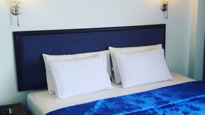 A neatly made bed with a dark headboard, two bedside lamps, and a floral-patterned bedspread.