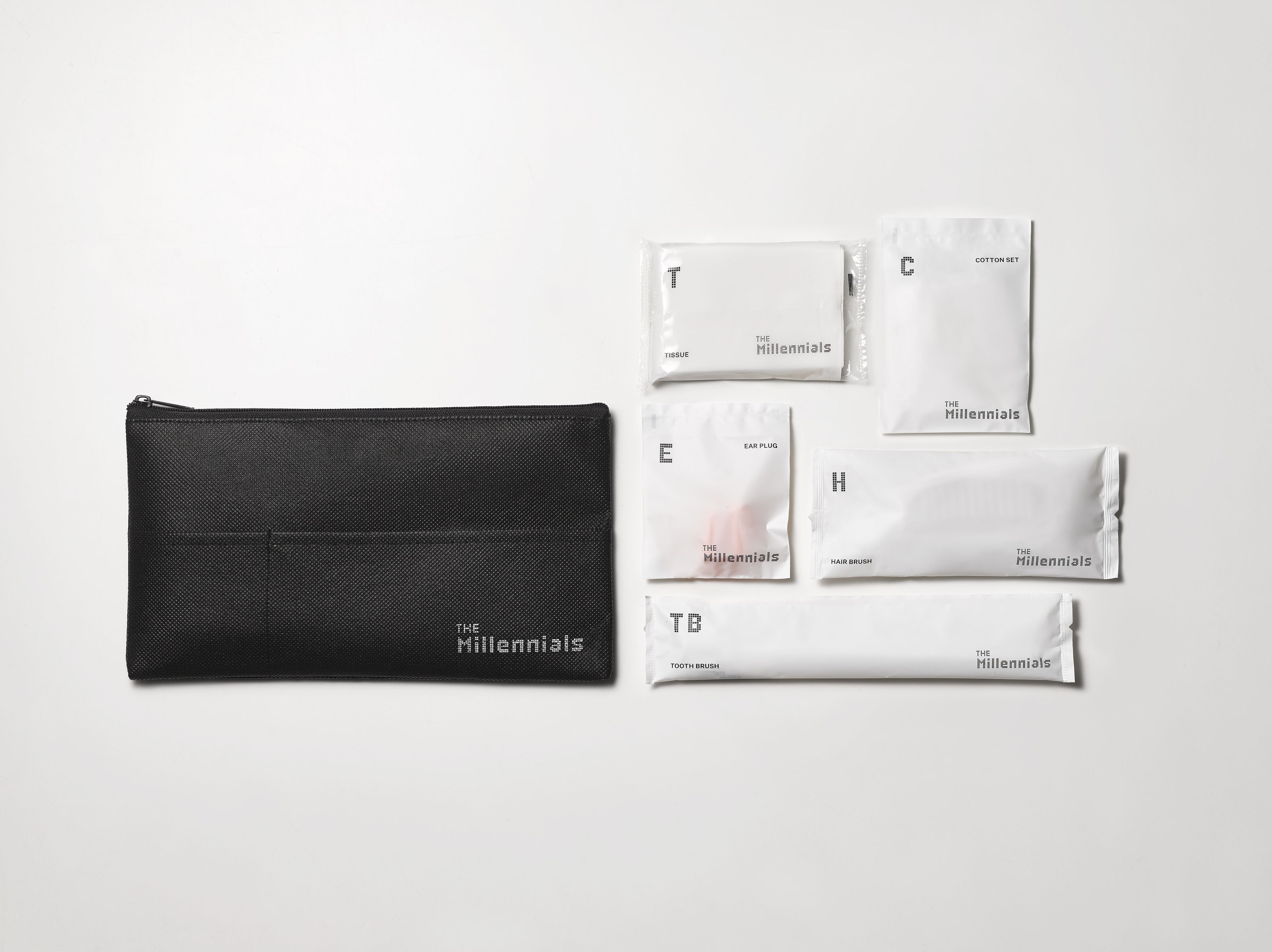 A black zippered pouch and five white packets labeled with items like tissue, ear plug, hair brush, and toothbrush.