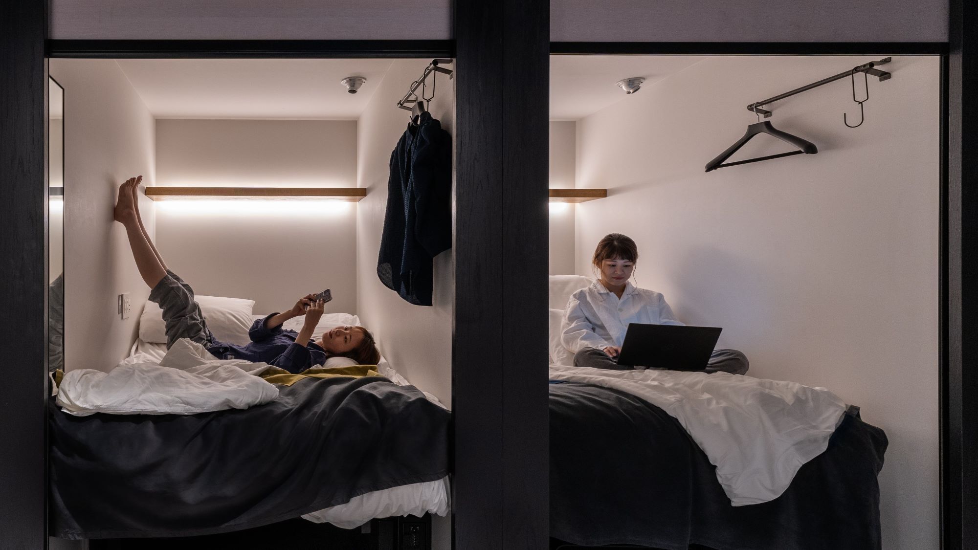 Una habitación de hotel con una cama, un perchero y un ordenador portátil sobre la cama.