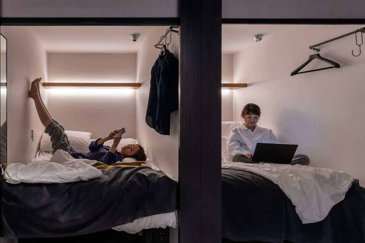 Quarto de hotel com uma cama, um cabideiro e um laptop sobre a cama.
