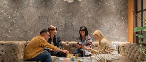 A group of people sitting on a leather couch in a room with a marble wall and a wooden floor.