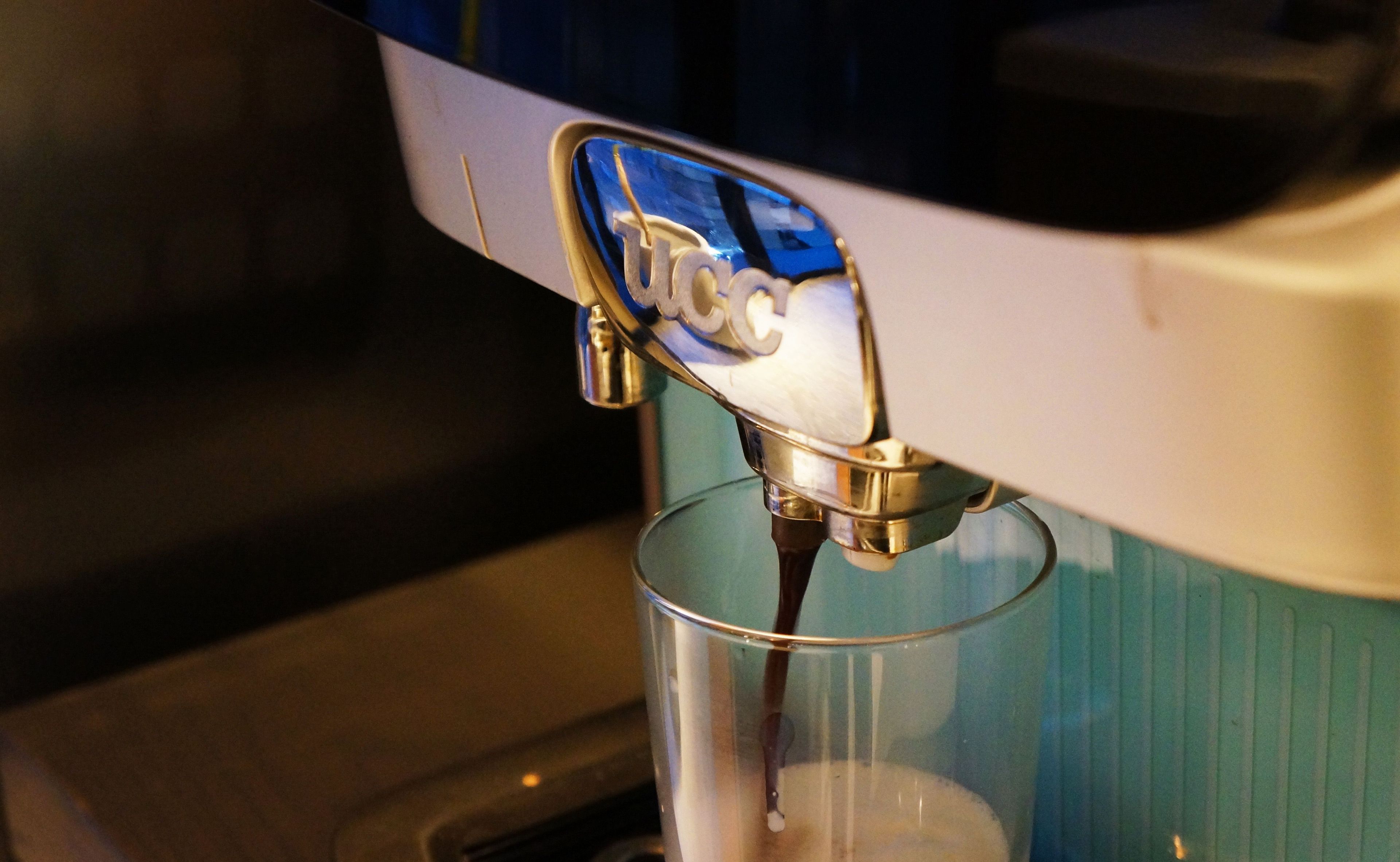 A coffee machine dispensing coffee into a clear glass cup.