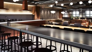 Een moderne keuken met een lang eiland, barstoelen en een zithoek met een bank en tafel.