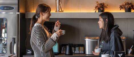 Una cocina moderna con electrodomésticos de acero inoxidable, una cafetera y plantas decorativas.