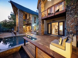 Una piscina al aire libre, sillones reclinables de piscina